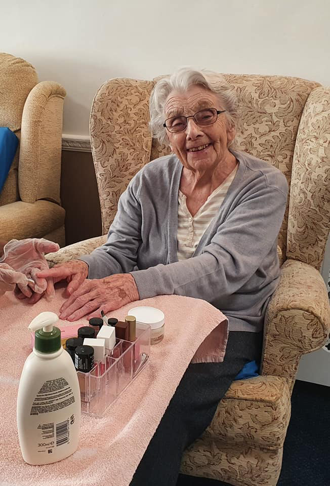 Elderly woman getting her nails painted in a care home