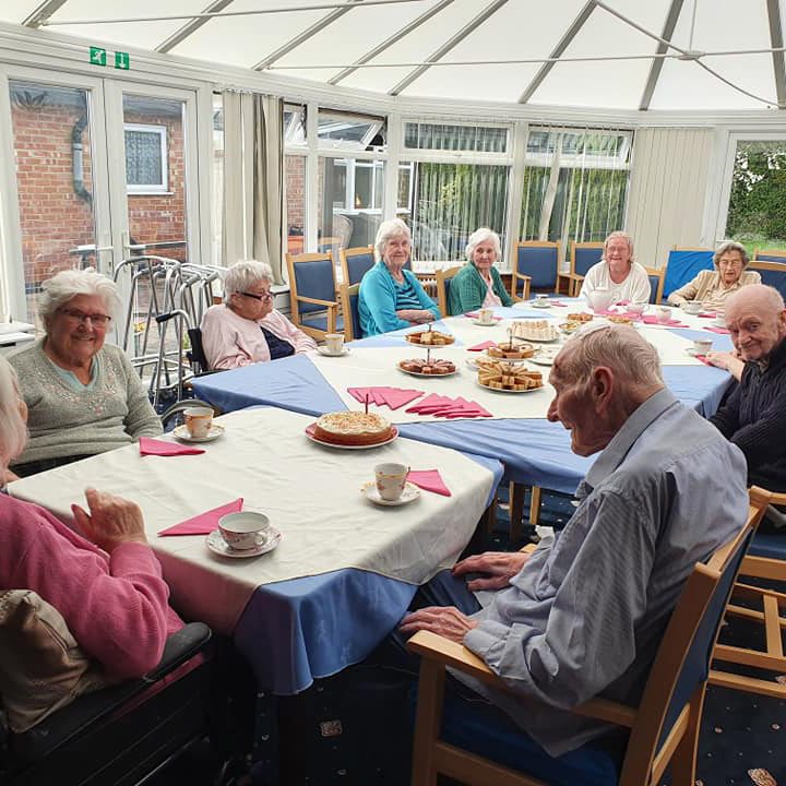 Elderly people in a care home having afternoon tea