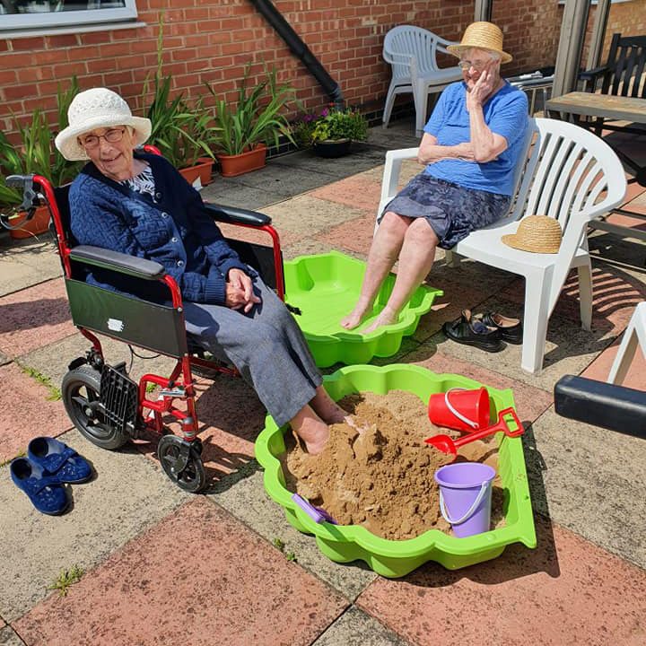 Two elderly woman keeping cool in the sun with a pool and sand pit