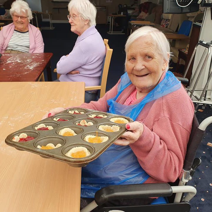 Elderly woman in an apron baking buns in a nursing home