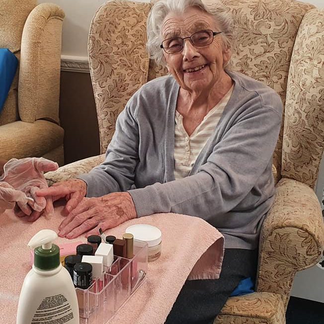 Elderly woman getting her nails painted in a care home