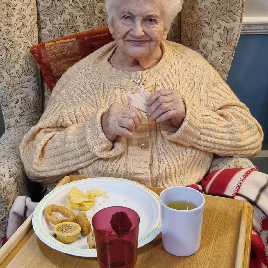 Elderly woman eating party food in a nursing home